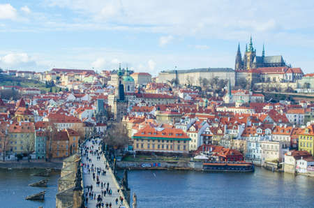 people are trying to cross charles bridge in prague in order to get to the famous prague castle, hradcany district and church of saint nicolas which are situated on the opposite shore of vltava / moldau river.のeditorial素材