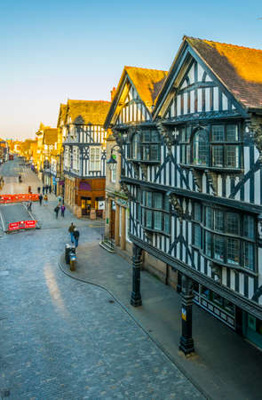 CHESTER, UNITED KINGDOM, APRIL 7, 2017: Traditional tudor houses alongside the Eastgate street in the central Chester during sunset, Englandのeditorial素材