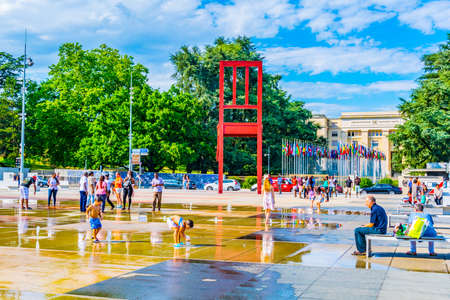 GENEVA, SWITZERLAND, JULY 20, 2017: Tourists are admiring sculpture of a Broken chair from Daniel Berste in front of the Palace of Nations in Geneva, Switzerlandのeditorial素材