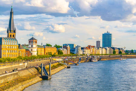 DUSSELDORF, GERMANY, AUGUST 10, 2018: People are strolling on riverside of Rhein in Dusseldorf with Saint Lambertus church, Germanyのeditorial素材
