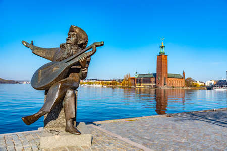 View of statue of Evert Taube with town hall of Stockholm in background, Swedenの写真素材