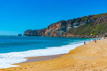 People are enjoying a sunny day on a beach in Nazare in Portugalの写真素材