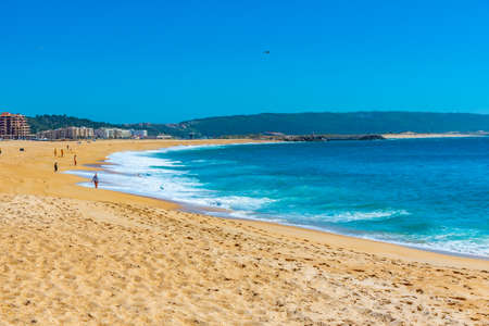 People are enjoying a sunny day on a beach in Nazare in Portugalの写真素材