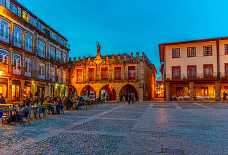 GUIMARAES, PORTUGAL, MAY 23, 2019: Sunset view of people strolling over Largo da Oliveria in the old town of Guimaraes, Portugalのeditorial素材
