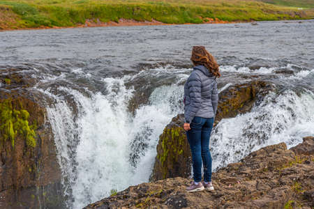 A woman looking at Kolufoss waterfall at Kolugljufur canyon on Icelandのeditorial素材