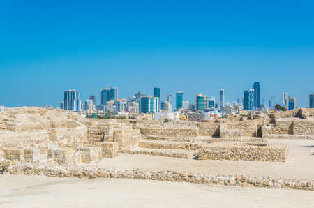 MANAMA, BAHRAIN, OCTOBER 22, 2016: View of the Bahrain fort complex with the Qal'At Al Bahrain fort with modern skyscrapers visible at horizon.のeditorial素材