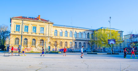 RUSE, BULGARIA, MARCH 7, 2015: group of children is plays football on a concrete pitch situated in areal of elementary school in ruse.のeditorial素材