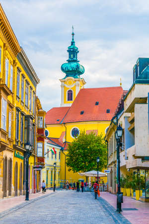 GYOR, HUNGARY MAY 20, 2016: View of people walking through a narrow street in old town of the hungarian city gyor towards the Carmelita Churchのeditorial素材