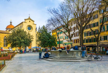 FLORENCE, ITALY, MARCH 15, 2016: a group of young people is sitting on a fountain in front of the church santo spirito in the italian city florence.のeditorial素材