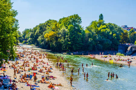 MUNICH, GERMANY, AUGUST 20, 2015: People enjoy sunny hot weather on the river banks of Isar river in bavarian city Munich. The river becomes a giant beach during hot days.のeditorial素材