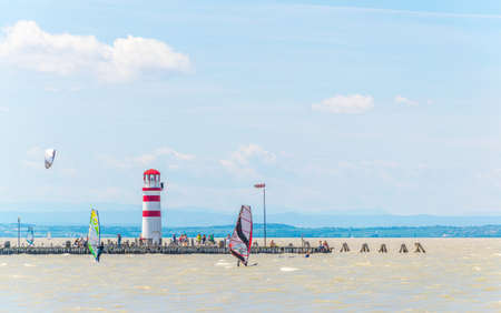 PODERSDORF, AUSTRIA, JULY 9, 2016: Young people are kite surfing near famous the red and white lighthouse in Podersdorf am See in Austria.town.のeditorial素材