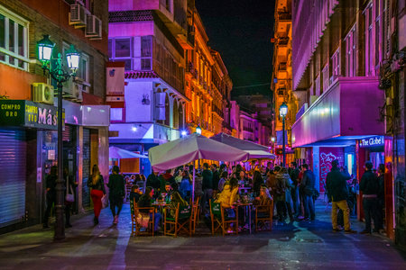 ALICANTE, SPAIN, JANUARY 2, 2016: View of a narrow street in the historical center of spanish city alicante where local people enjoy nightlife in front of many bars.のeditorial素材