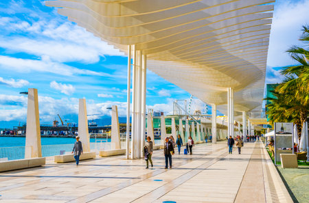 MALAGA, SPAIN, JANUARY 4, 2016: people are walking on the paseo del muelle dos promenade in spanish city malaga which stretches through port under a construction resembeling white waveのeditorial素材