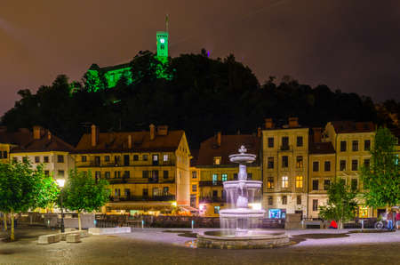 LJUBLJANA, SLOVENIA, JULY 29, 2015: Novi trg - New city square in the slovenian capital Ljubljana is overlooked by a castle situated on a hill across ljubljanica river during a night in July.のeditorial素材