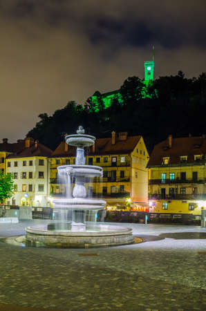 LJUBLJANA, SLOVENIA, JULY 29, 2015: Novi trg - New city square in the slovenian capital Ljubljana is overlooked by a castle situated on a hill across ljubljanica river during a night in July.のeditorial素材