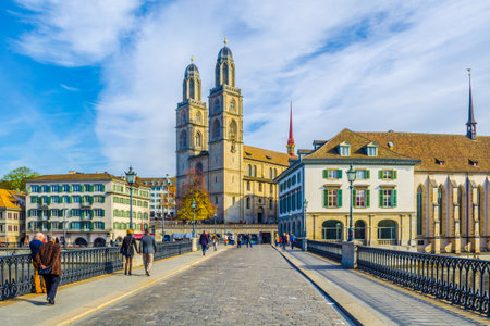 ZURICH, SWITZERLAND, OCTOBER 24, 2015: people are crossing bridge in front of the grossmunster cathedral in zurich during sunny day in autumnのeditorial素材