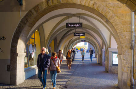 ZURICH, SWITZERLAND, OCTOBER 25, 2015: people are walking through an arcade under grossmunster catherdral in swiss city zurichのeditorial素材