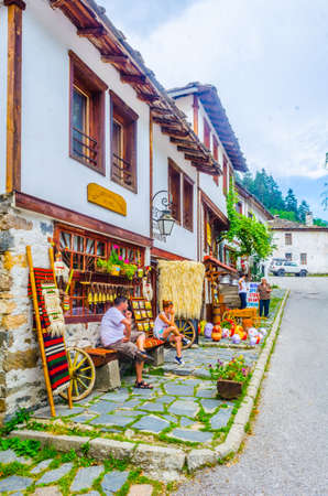 SHIROKA LAKA, BULGARIA, AUGUST 1, 2014: People are sitting on a bench on the main square of Shiroka Laka village in Bulgariaのeditorial素材
