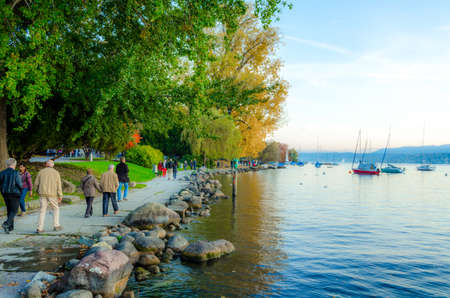 ZURICH, SWITZERLAND, OCTOBER 24, 2015: people are walking on a sunny promenade along the zurich lake in switzerland during late autumn afternoonのeditorial素材