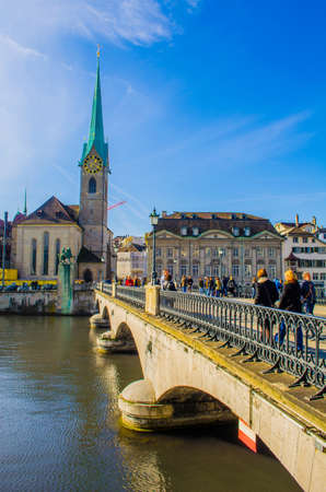 ZURICH, SWITZERLAND, OCTOBER 24, 2015: people are crossing bridge in front of the grossmunster cathedral in zurich during sunny day in autumnのeditorial素材