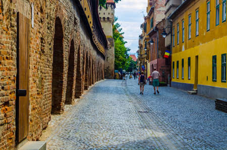SIBIU, ROMANIA, JULY 6, 2015: Unidentified people wander along the medieval defense wall and The Carpenters' Tower in Sibiu city where a lot of small streets remind medieval character of this city partのeditorial素材