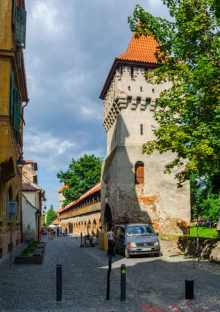 SIBIU, ROMANIA, JULY 6, 2015: Unidentified people wander along the medieval defense wall and The Carpenters' Tower in Sibiu city, Transylvania region, Romania.のeditorial素材