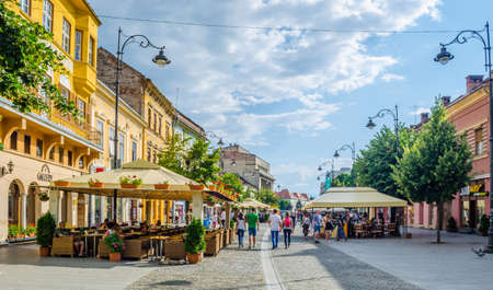 SIBIU, ROMANIA, JULY 6, 2015: people stroll along the boulevard nicolae balcescu or enjoy a sunny...