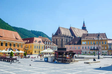 BRASOV, ROMANIA, JULY 6, 2015: Council Square is historical center of city, people walking and sitting at outdoor terraces and restaurants.のeditorial素材