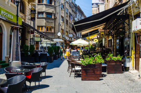 BUCHAREST, ROMANIA, JULY 11, 2015: view of a minor street inside of the old town of romanian capital Bucharest where people usually relax during hot summer days.のeditorial素材