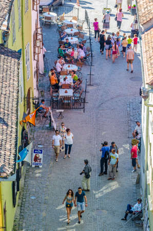 SIGHISOARA, ROMANIA, JULY 6, 2015: People are walking on a narrow street towards cetatii square in romanian city sighisoaraのeditorial素材