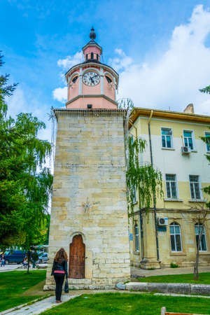 BYALA, BULGARIA, MAY 3, 2016: A young woman is standing in front of a clock tower in the bulgarian city Byala.のeditorial素材