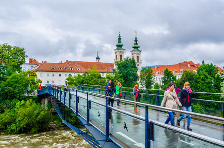 GRAZ, AUSTRIA - JULY 30, 2015: People are crossing river mur in austrian city graz in direction from the mariahilher church.のeditorial素材