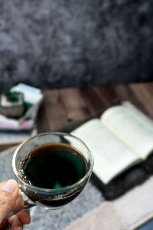 Hand holding coffee cup In the bedroom in the morning with booksの写真素材