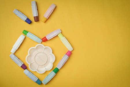 Watercolor tubes, placed in the shape of a heart, on a yellow background, taken from the top, with gaps.の写真素材