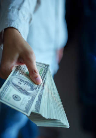 Man's hand,holding dollar bill, handing over ,in black background, concept ,investment, profit,...