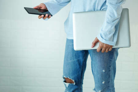 Walk, holding a laptop, and mobile phone, at thigh level, in the lower half of the body, horizontally.の写真素材