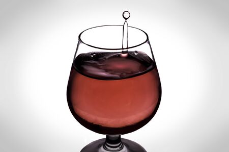The falling drops of water into the wine glassの写真素材