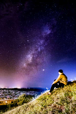 Man sitting on the top of a hill and looking at the milky wayの写真素材