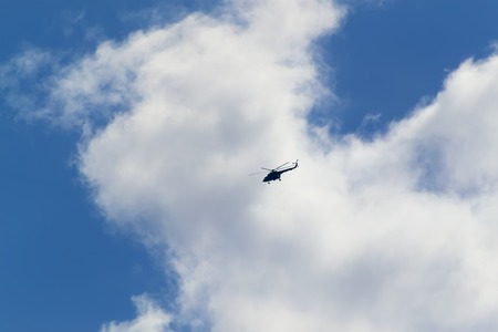 A helicopter flies high in the skyの写真素材