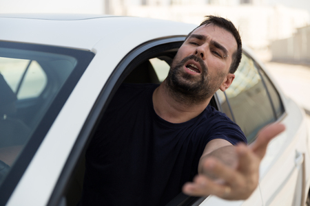 Angry driver pissed off by drivers in front of him and gesturing with hands. Road rage traffic jam concept.  Angry man driving a vehicle is expressing his road rage.の写真素材