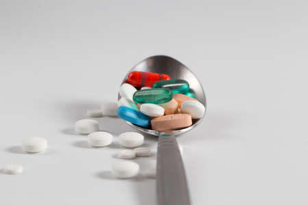 Isolated spoon full of medicine with pills and capsules on white background with copy space. Concept of overdose and cost of treatment. Concept of expensive treatmentの写真素材