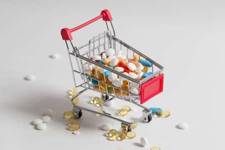 Isolated shopping cart full of medicine with pills and capsules. Concept of overdose and cost of treatment. Concept of expensive treatmentの写真素材
