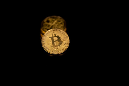 Stack of golden bitcoins isolated on black background with reflection. Cryptocurrency concept with copy space.の写真素材