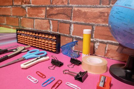 School supplies on pink board and brick background. Education, back to school concept with copy...