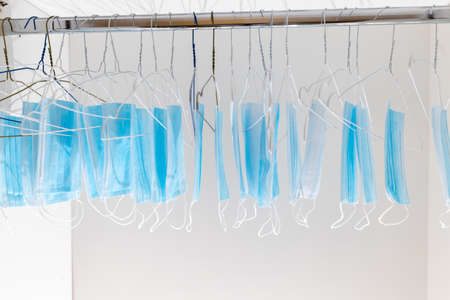 Disposable surgical masks hanging on hangers in a wardrobe closet. Concept of new normal. Concept of waring a mask becoming e new habit. Concept of adaptation during crisis and pandemic due to Covid.の写真素材