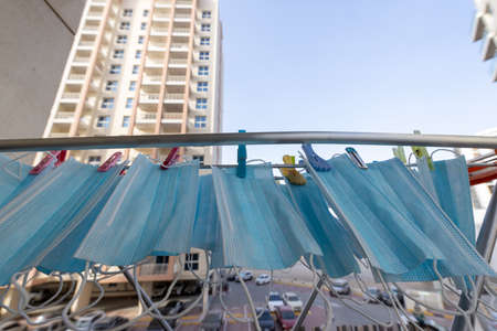 Blue disposable surgical mask washed and hanging on a drying rack. Concept of shortage of personal protection equipment (PPE). Concept of re usability and recycling during crisis times.の写真素材