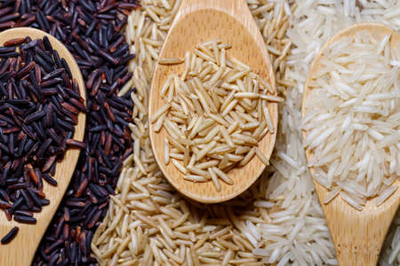 Black wild rice, brown wild rice and white jasmine rice in wooden spoon flat lay. Creative layout. Food conceptの写真素材