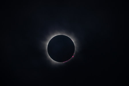 A stunning view of a solar eclipse, showcasing the dark silhouette of the moon completely covering...