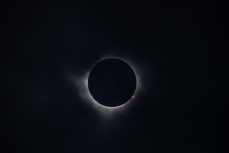A stunning view of a solar eclipse, showcasing the moon completely covering the sun, with a halo of light around the edges and a dark sky in the background.の写真素材