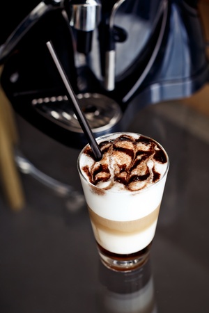 Latte macchiato coffee with chocolate decoration and straw